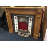 An art nouveau cast iron chimneypiece with later pine surround, the tiled insert with stylised