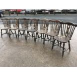 A set of seven yoke back dining chairs, with pierced splats framed by spindles above solid saddle