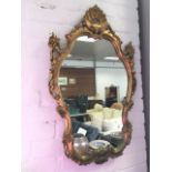 A rococo style gilt framed mirror in scrolled pierced frame, having shell crest.