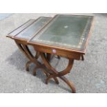 A nest of three mahogany tables with gilt tooled rectangular skiver tray tops on crossed sabre legs.