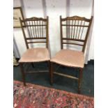 A pair of Edwardian mahogany chairs, the back rails on slender spindles inlaid with foliate