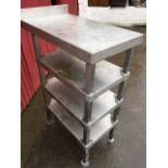 A rectangular Stellex stainless steel stand with four tiers on square columns.