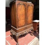 A Queen Anne style burr walnut cocktail cabinet with gadrooned carved caddy top above quarter