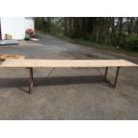 A12ft rectangular pine trestle table, the plank top on folding legs with metal supports.