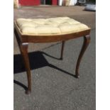 A button upholstered dressing table stool raised on slender tapering cabriole legs.