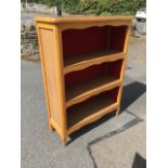 A open bookcase with scalloped rectangular top having shaped aprons to shelves, with panelled