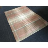 A pink ground woven tartan rug, with hessian style backing.