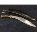 A brass handled kukri knife in leather sheath with shaped steel blade, complete with two small