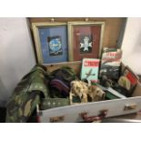 A suitcase of militaria including two framed regimental badges, books on World War 1 & II