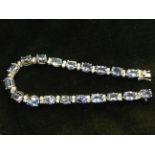 An 18ct tanzanite & diamond bracelet with twenty claw set oval tanzanite stones weighing over