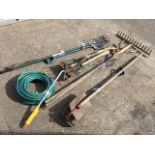 A quantity of garden tools including a fork, spades, rakes, hoes, a length of garden hose, etc. (A