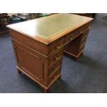 A reproduction mahogany kneehole desk, the rectangular moulded top with gilt tooled skiver above