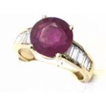 A large claw set 18ct gold ruby & baguette cut diamond ring, the circular claw set ruby of over