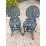 A pair of garden chairs, the arched backs with oval pierced leaf panels above circular grill