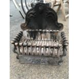 A cast iron dog grate, the rectangular basket on paw feet with scrolled sides, the fireback cast