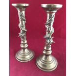 A pair of oriental brass candlesticks, the columns on circular moulded bases, cast with entwined