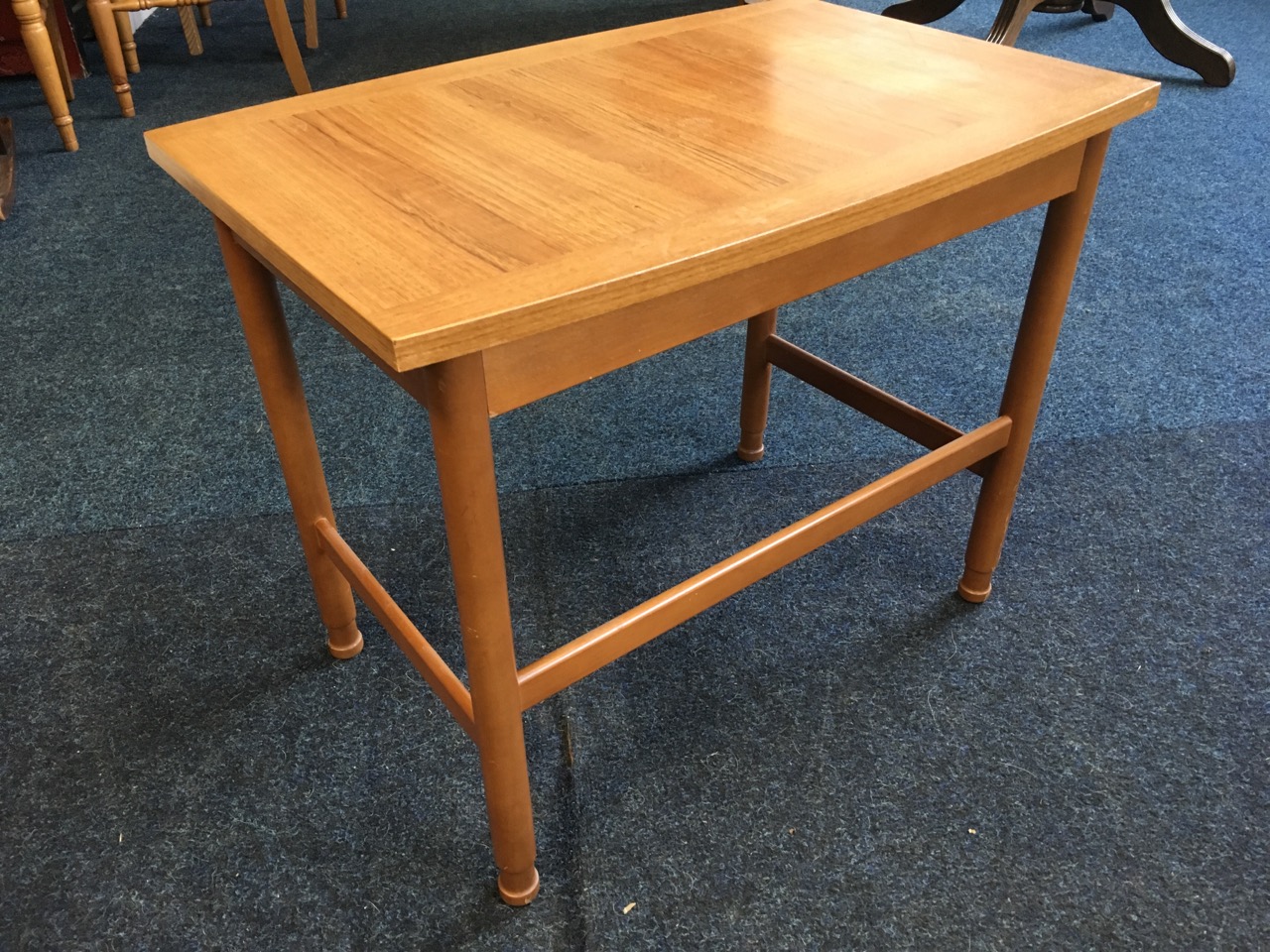 A 70s teak coffee table by Schreiber, the elliptical rectangular top on turned column legs joined by