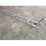 An aluminium roof ladder with roller wheels and ribbed treads.