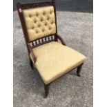 A late Victorian carved walnut chair with button upholstered back above spindles, having sprung