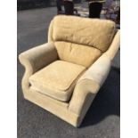 A large upholstered armchair with loose cushions and padded arms, raised on casters.