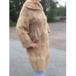 A ladies pale mink fur coat with wide collar and cuffs, pockets and lining.