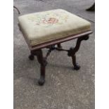 A Victorian rosewood stool with square floral needlework seat on scroll carved legs with acanthus