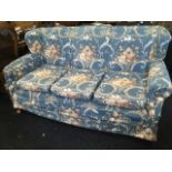 A three seater winged sofa with loose cushions & covers raised on turned feet with later