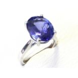 A platinum tanzanite ring, the single oval claw set stone of nearly five carats, raised in a cage on