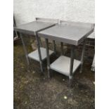 A pair 2ft of stainless steel food preparation tables, the tops with upstands on tubular legs joined