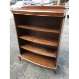 A bowfronted mahogany open bookcase, with moulded top above adjustable open shelves, raised on