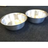A pair of large circular aluminium bowls with rolled rims. (2)