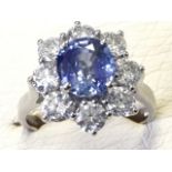 An 18ct gold sapphire & diamond cluster ring, the large blue claw set oval sapphire weighing