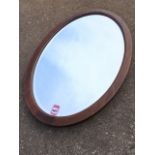 An oval mahogany framed mirror with bevelled plate.