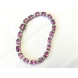 An 18ct gold sapphire & diamond bracelet, the nineteen pink claw set sapphires weighing over