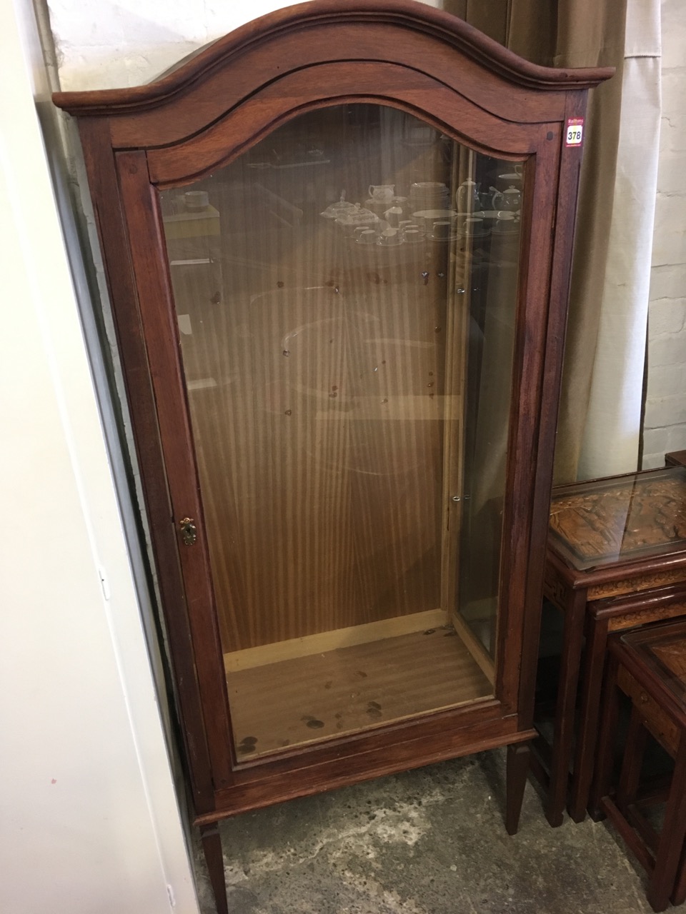 A glazed vitrine with arched moulded cornice above a glass dowel jointed cupboard door, with glass