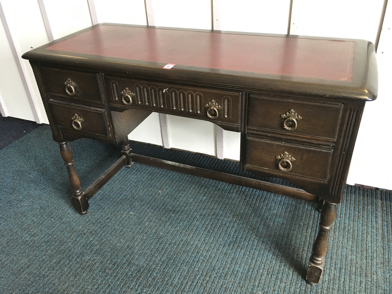 An oak kneehole desk, the cushion moulded top set with skiver above a chisel carved frieze drawer