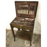 An oak cased canteen of silver plated cutlery, the side table with moulded top enclosing box with