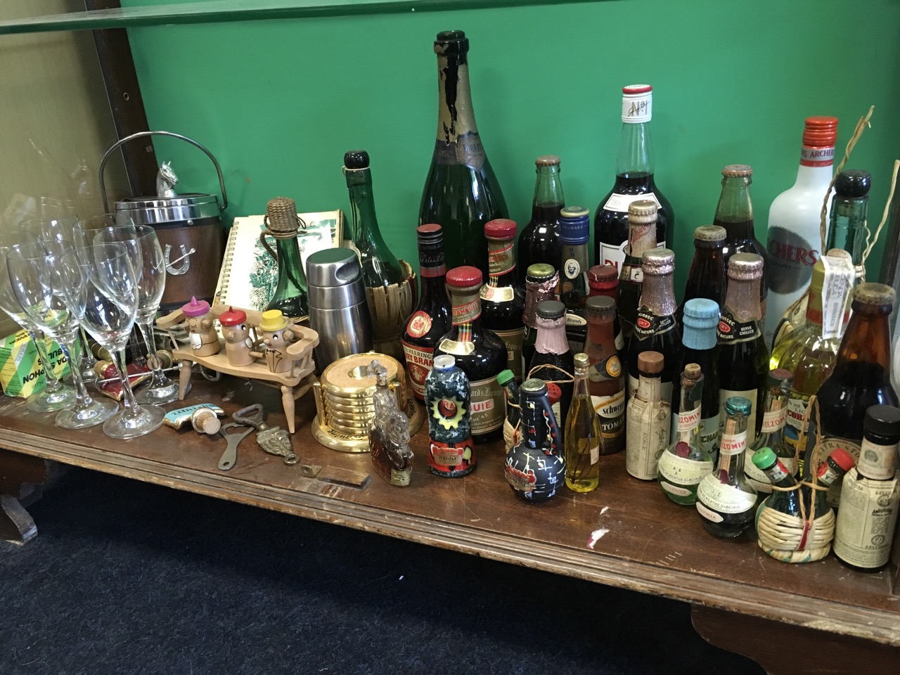 The contents of a booze cupboard including miniatures, bottled beer, unopened spirits, a cocktail