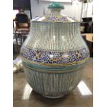 A large North African pot with waisted cover having bun shaped handle, hand decorated with blue