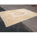 An Indian wool carpet woven in a traditional foliate design in gold on ivory ground, having