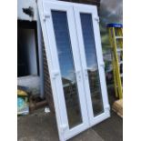 A pair of unused patio doors, with rectangular double glazed panels in frames, complete with keys.