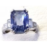 An 18ct gold sapphire & diamond ring, the emerald cut claw set sapphire of over seven carats mounted