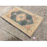 An oriental style rug woven with scalloped floral medallion and pendants in green field framed by