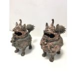 A pair of bronze Chinese temple censors, the verdigris animals cast as traditional ceremonial dogs