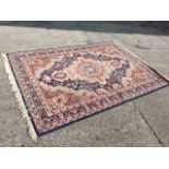 An oriental style rug woven with oval floral scalloped medallion in blue field framed by