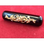 A Victorian onyx mourning brooch, the rectangular rounded bar set with gold scrolled mount and