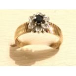 A 9ct gold hallmarked sapphire & diamond cluster ring, the oval claw set sapphire framed by six