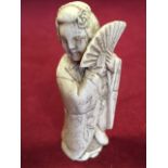 A carved ivory netsuke depicting a geisha lady with fan, having engraved floral decoration to