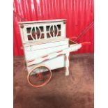 A childs barrel organ, the painted cart with spoked wheels and shaped handles, mounted with music