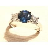 An 18ct gold three stone sapphire & diamond ring, the round claw set sapphire weighing just under